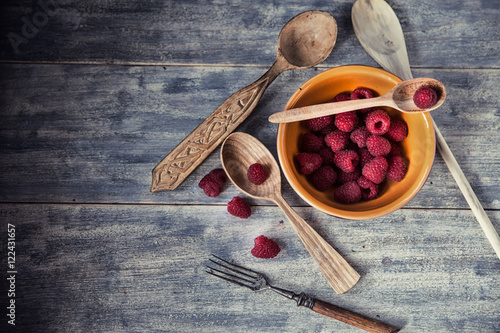 Ripe sweet raspberries in bowl on wooden table. Close up, top vi