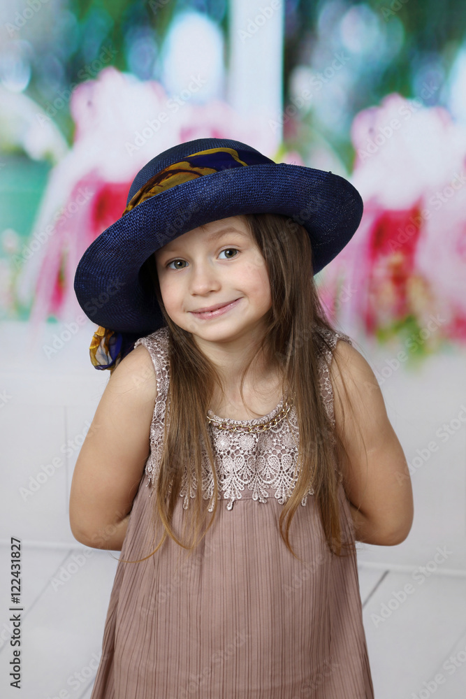Cute little girl in too big hat hides hands behind back - surprise or secret, does not want to show Cute little girl in too big hat hides hands behind back - surprise or secret, does not want to show