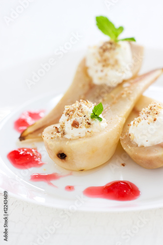 Homemade poached pear with whipped cream, nuts, mint, honey and jam, closeup