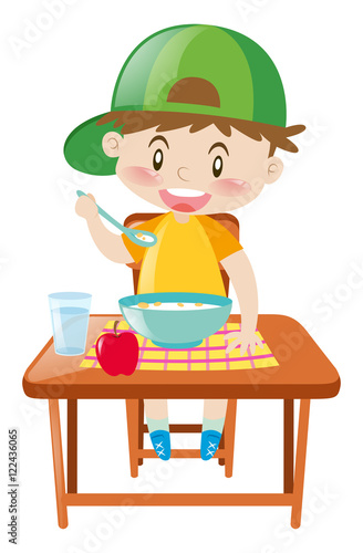 Little boy at dining table eating breakfast