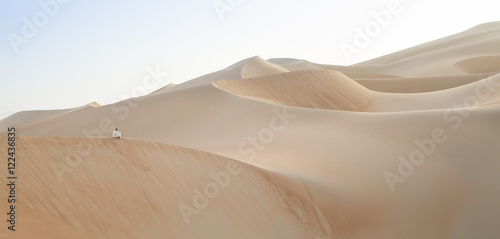 Man in kandura in a desert at sunrise photo