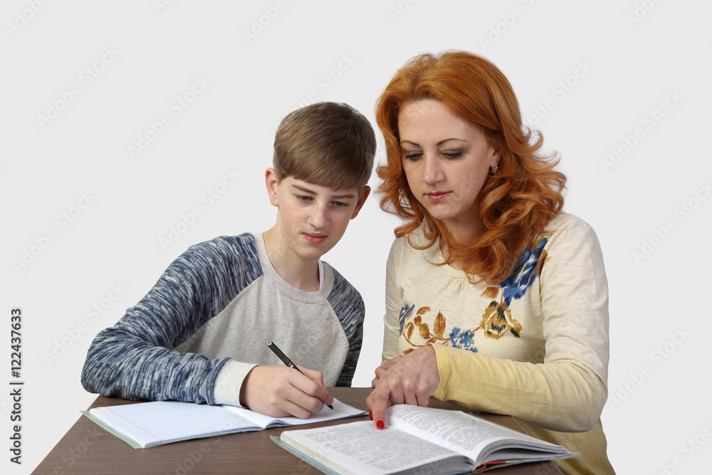 Redhead woman helps boy to do homework on gray background - Education in family, mother and son Redhead woman helps boy to do homework on gray background - Education in family, mother and son