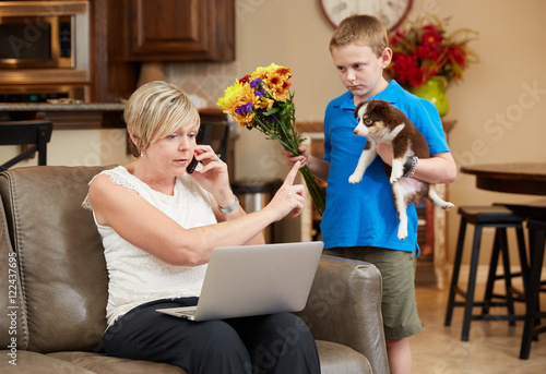Distracted Working Mother On Electronics, Ignoring Sad Son Holding Puppy