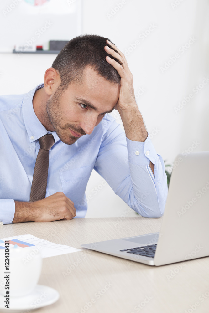 Fototapeta premium Stressed businessman working at his desk in his office