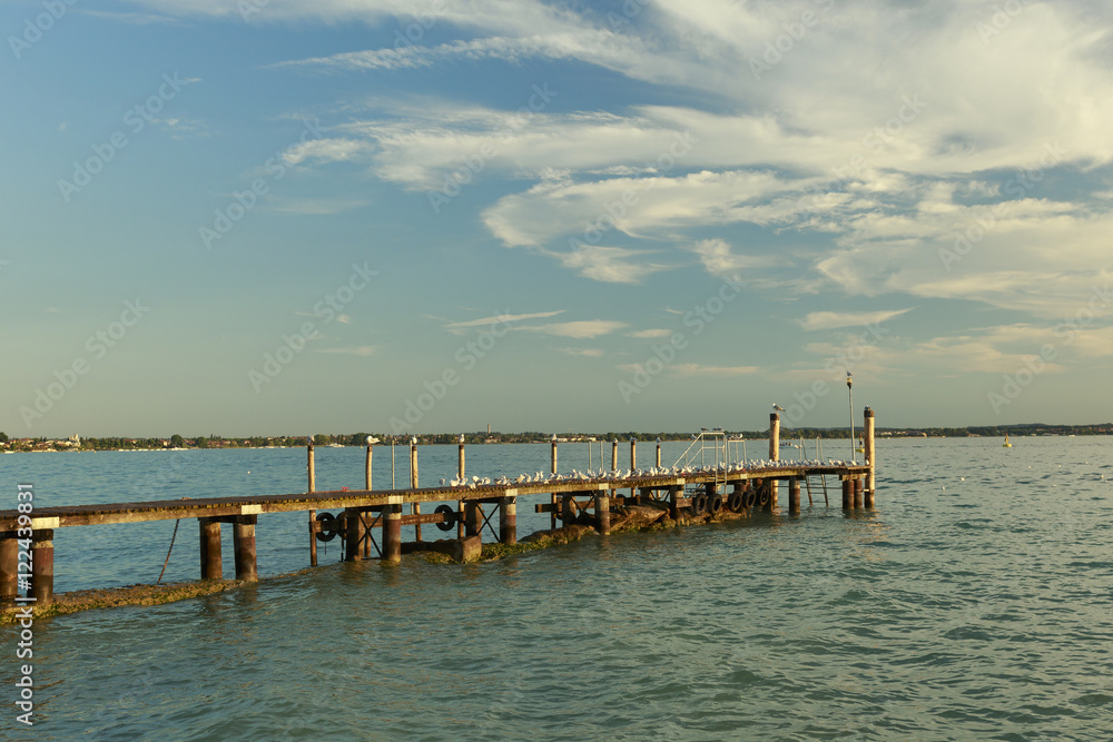 Wooden dock al lake with seagulls, Lake of Garda, Italy