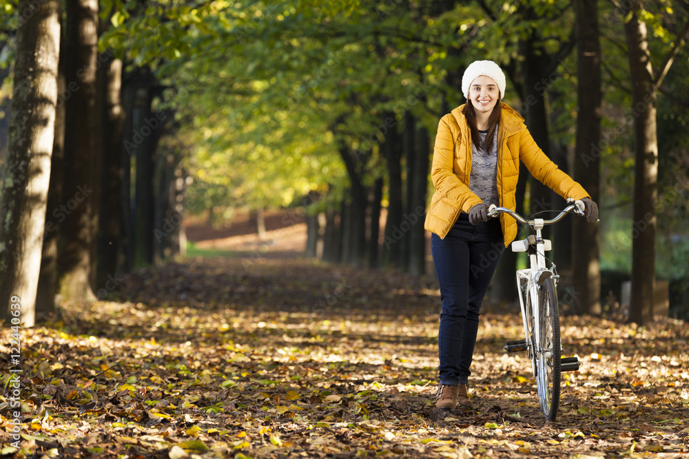 Obraz premium Beautiful young woman walking with bicycle in Autumn park