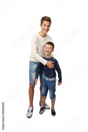 Happy teenage boy plays with his joyful little brother isolated on white background