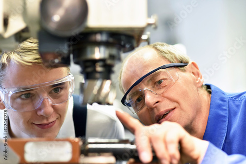Berufsausbildung im Handwerk: Jugendlicher und Lehrer an einer CNC Maschine photo