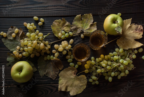 Two glasses with wine, apples and grapes on wooden surface photo