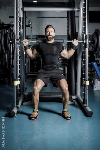 Hombre con grandes músculos levantando peso mientras entrena en el gimnasio. Ponerse en forma.