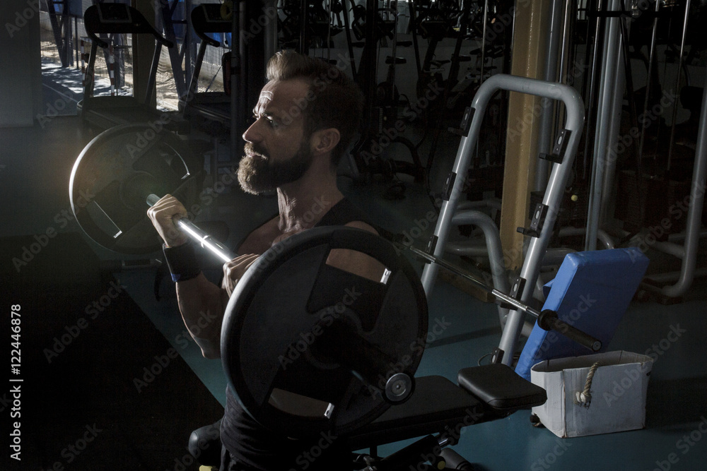 Hombre con grandes músculos levantando peso mientras entrena en el gimnasio. Ponerse en forma. Hombre con grandes músculos levantando peso mientras entrena en el gimnasio. Ponerse en forma.