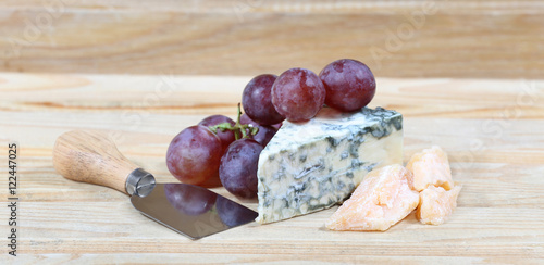 Delicious cheese and grape on natural wooden background