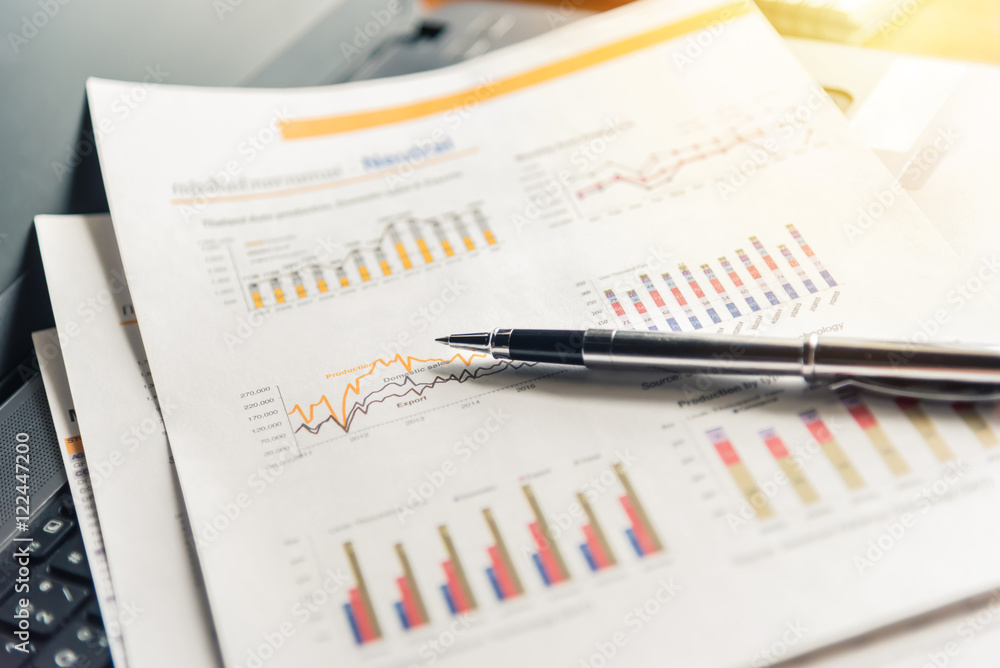 Financial documents and pen on laptop with sunlight filter effect. Financial documents and pen on laptop with sunlight filter effect.