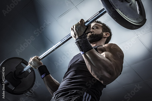 Hombre con grandes músculos levantando peso mientras entrena en el gimnasio. Ponerse en forma.
