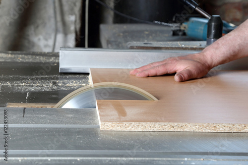 Carpenter cuts the board on rotating circular saw blade - Worker hands close up