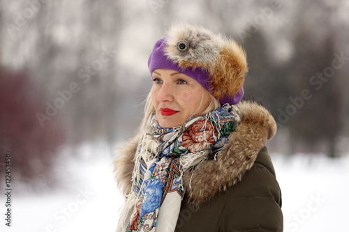 Mature woman in purple beret and winter clothes on blur natural snowy background