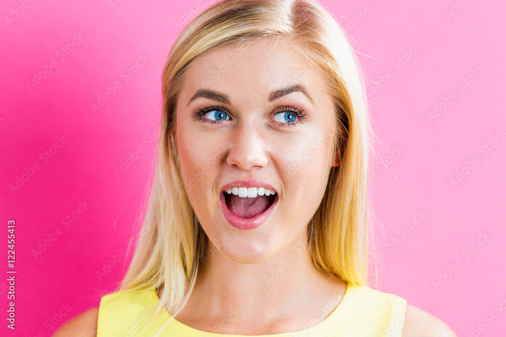 Happy young blonde woman on a pink background