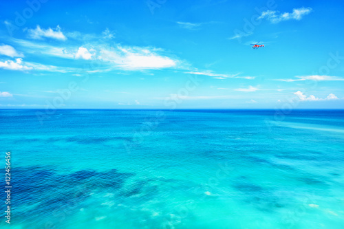 Small red helicopter in blue sky blue ocean horizon
