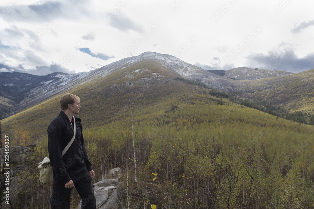 Naklejka premium Traveler in the mountains on the background of mountain landscape looking into the distance