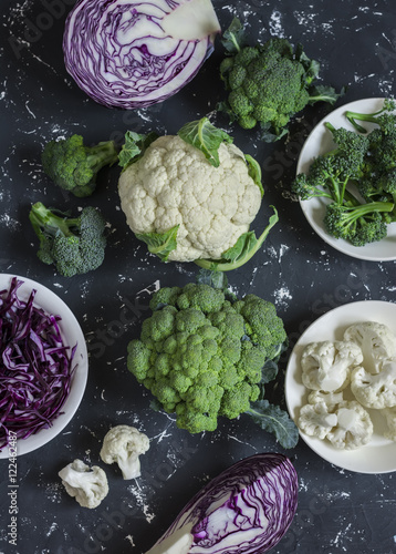 Variation of fresh cabbage - broccoli, cauliflower, red cabbage. On a dark background, top view
