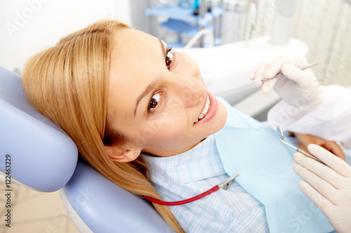 A young woman sitting in dentist chair  looking at camera and smiling