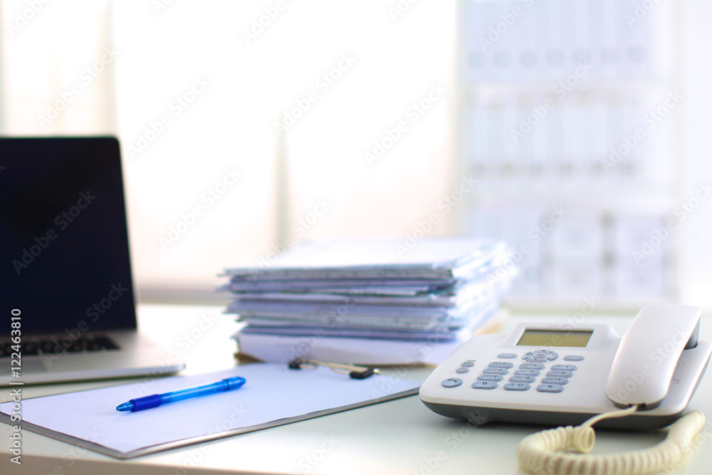 Laptop with stack of folders on table white background Laptop with stack of folders on table white background