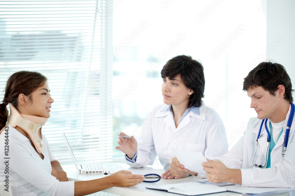 Two doctors explaining diagnosis to their female patient Two doctors explaining diagnosis to their female patient