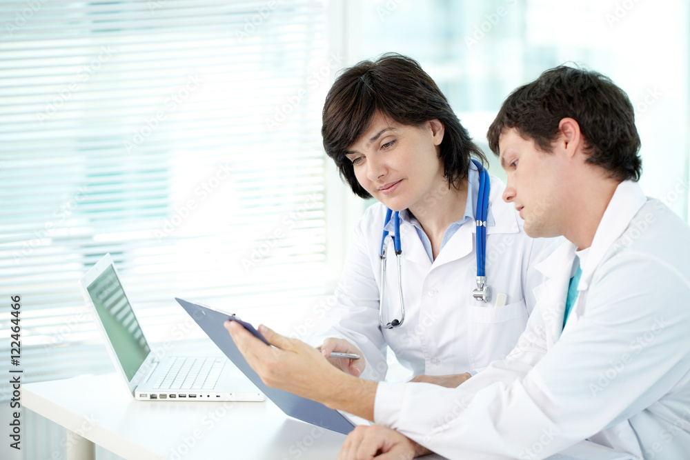 Two doctors examining test result in office Two doctors examining test result in office