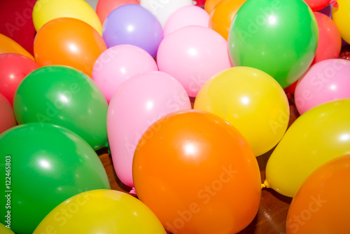 Close-up detail of brightly colored balloons on a wooden floor. Party and dance celebration background concept. © substancep