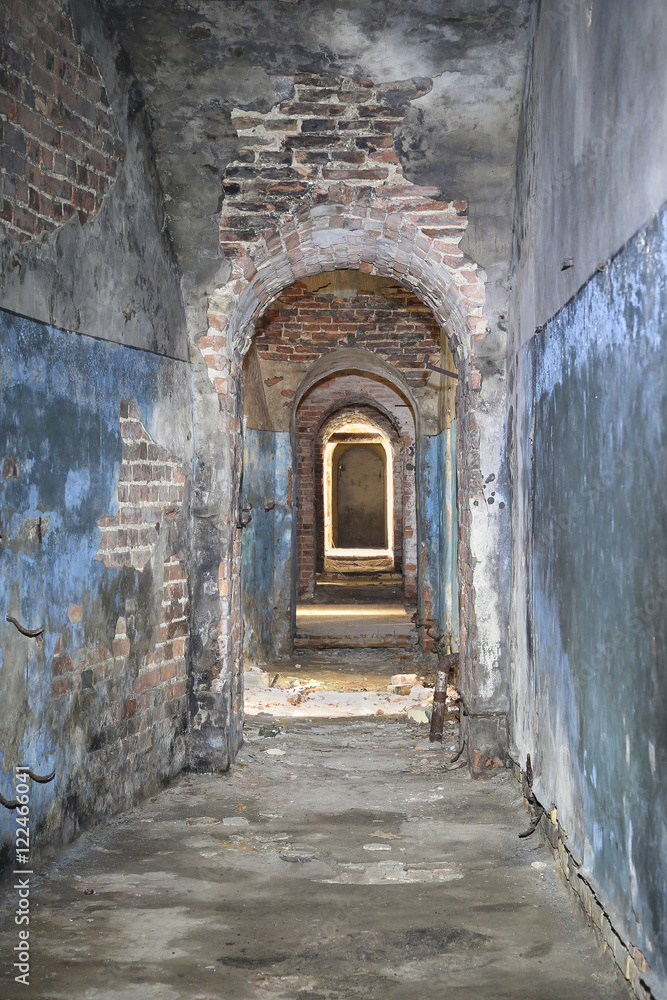 Narrow corridor in old fortress basement with brick ceiling and broken stones strewn on floor - ancient dungeons
