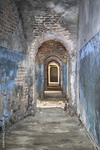 Narrow corridor in old fortress basement with brick ceiling and broken stones strewn on floor - ancient dungeons