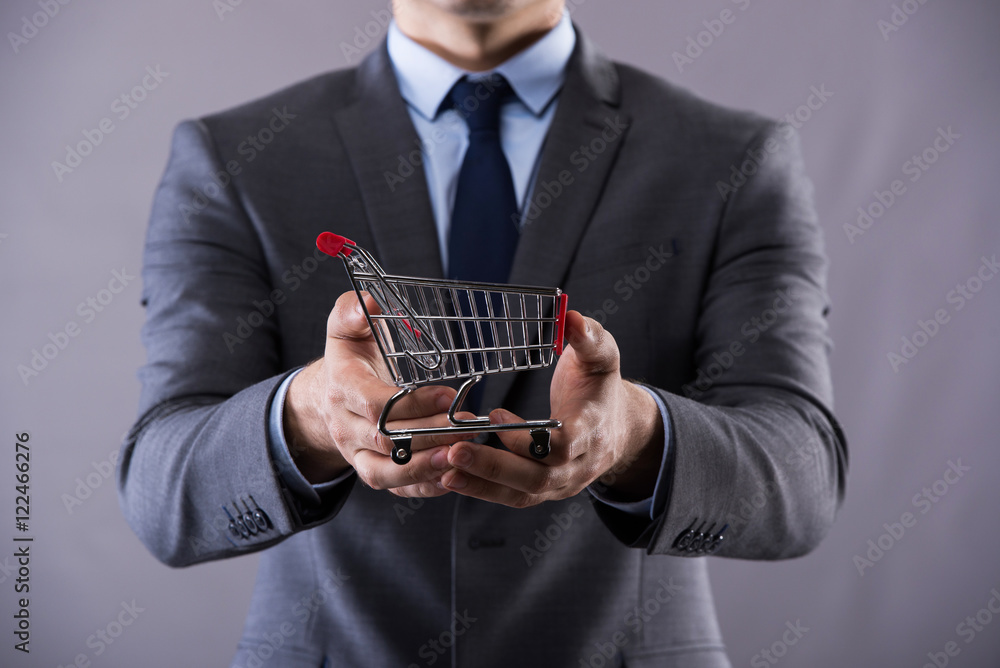 Buisinessman holding shopping cart in online shopping concept Buisinessman holding shopping cart in online shopping concept