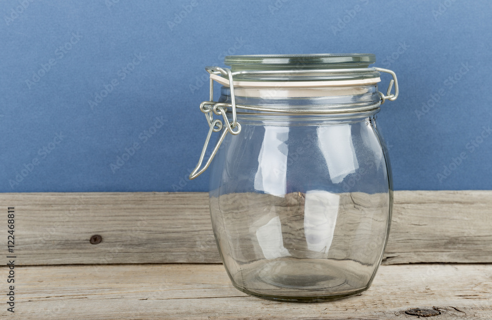 Empty glass jar with cap hold with metal wire  on the wooden floor