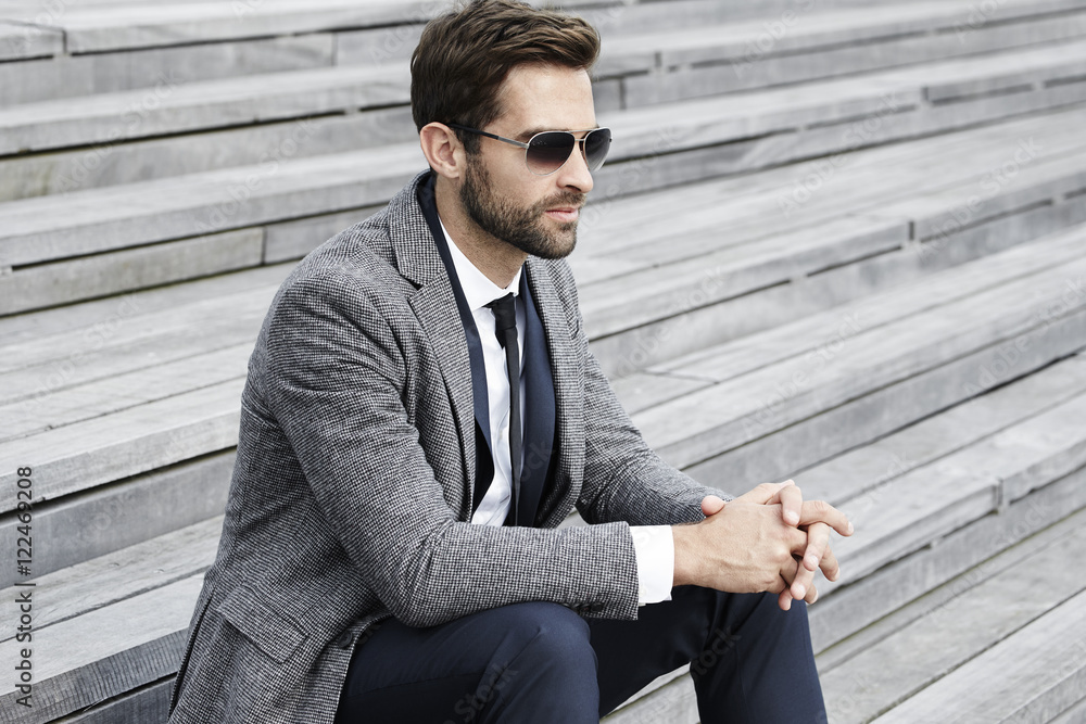 Businessman thinking on steps outdoors Businessman thinking on steps outdoors