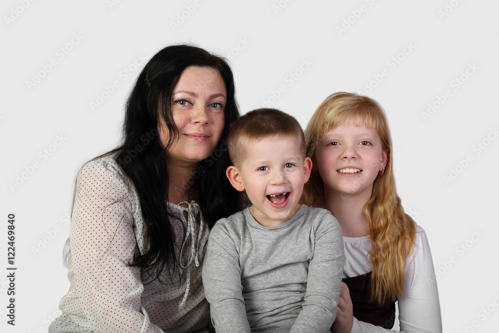 Little blonde girl and toothless boy with brunette woman on gray background - mother, son and daughter - family relations and love concept Little blonde girl and toothless boy with brunette woman on gray background - mother, son and daughter - family relations and love concept