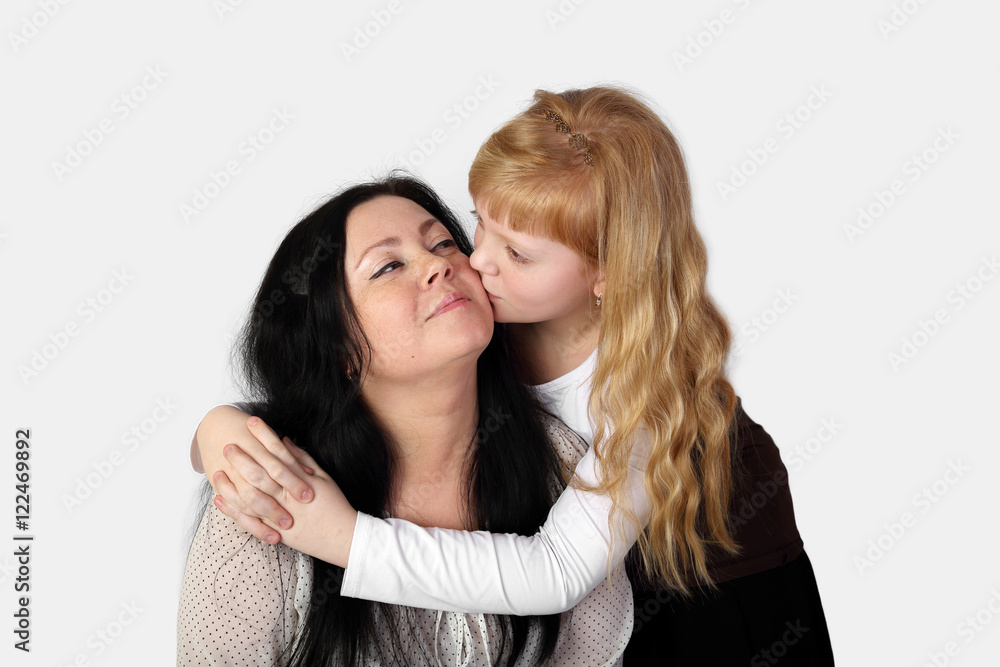 Teenage blonde girl kiss happy smiling woman on gray background - daughter love her mother Teenage blonde girl kiss happy smiling woman on gray background - daughter love her mother