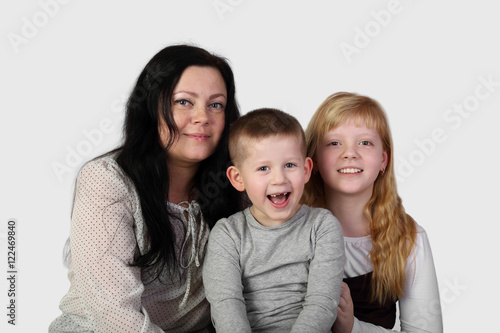Little blonde girl and toothless boy with brunette woman on gray background - mother, son and daughter - family relations and love concept