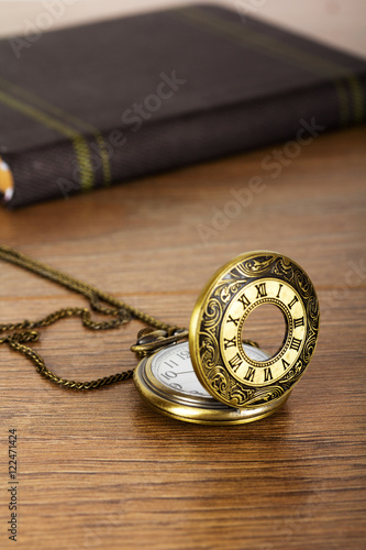 Pocket watch and book against a rustic background