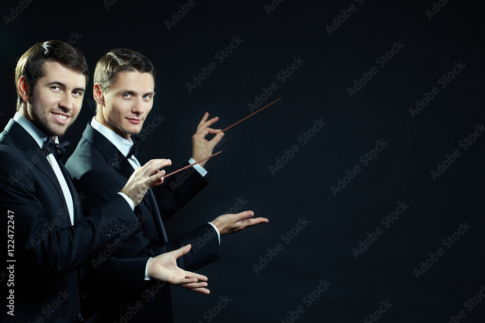 Φωτογραφία Two men in tuxedoes waving wands and looking at camera