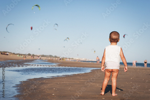 Naked baby in sleeveless shirt on beach photo