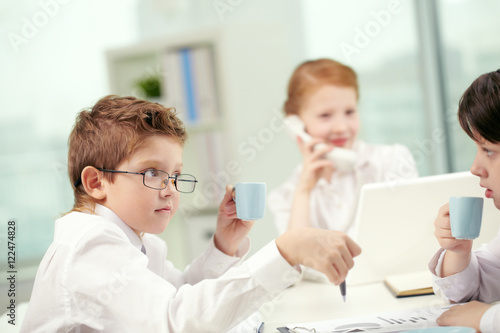 Little children drinking coffee in office and communicating