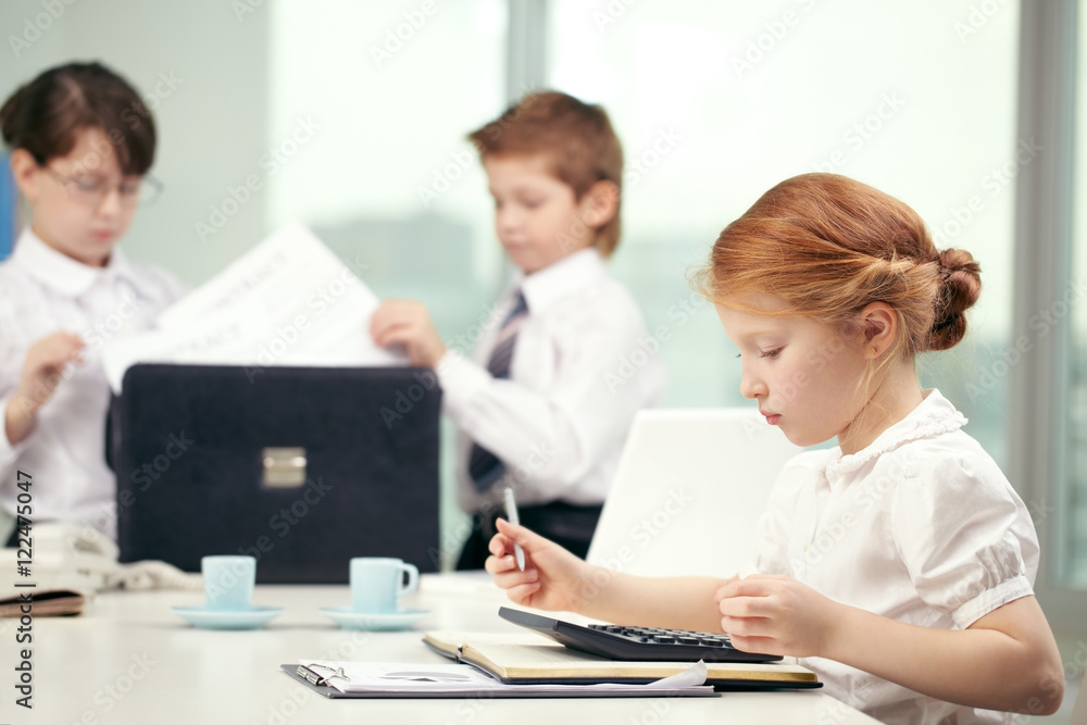 Little cute red hair girl working with calculator in office Little cute red hair girl working with calculator in office