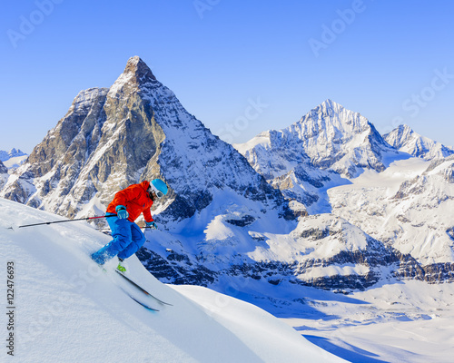 Skier skiing downhill in high mountains in fresh powder snow. Sn