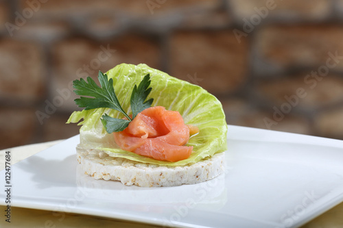 Sharply focused close up of fresh salmon canape on blurred stone wall background. Image for a restaurant snack menu or party invitation cover design