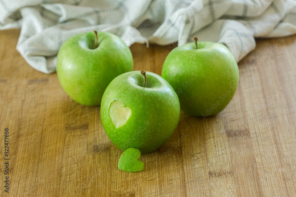 Tres manzanas en una mesa de madera con un corazon (concepto de dieta y salud) Tres manzanas en una mesa de madera con un corazon (concepto de dieta y salud)