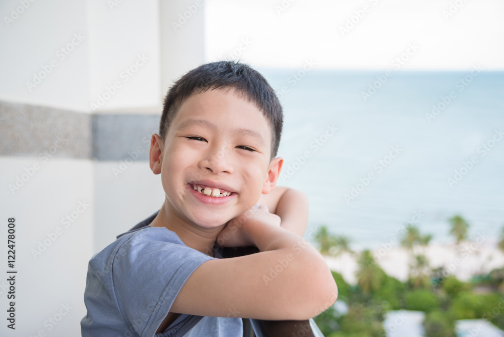 Young asian boy standing at balcony and smiles Young asian boy standing at balcony and smiles