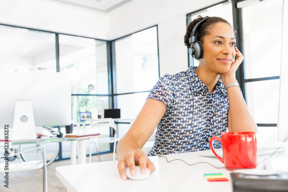 Portrait of smiling afro-american office worker sitting in offfice with headphones Portrait of smiling afro-american office worker sitting in offfice with headphones