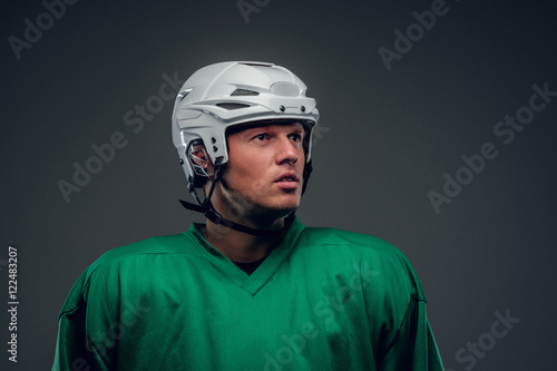 Portrait of hockey player on grey background.