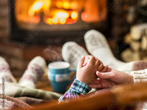 Warming and relaxing near fireplace. Mother and daughter holding