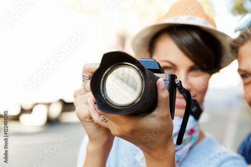 Outdoor summer smiling lifestyle portrait of pretty young woman with camera